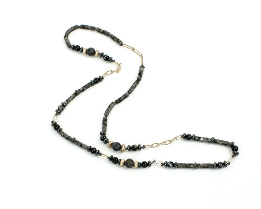 Necklace with black beads and gold chain on a white background